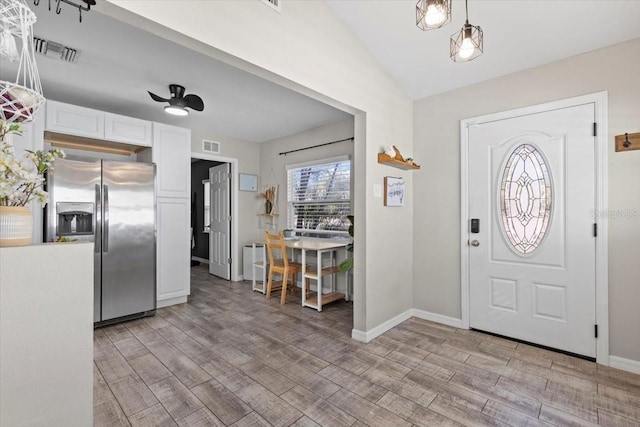 foyer entrance with vaulted ceiling, baseboards, visible vents, and light wood-type flooring