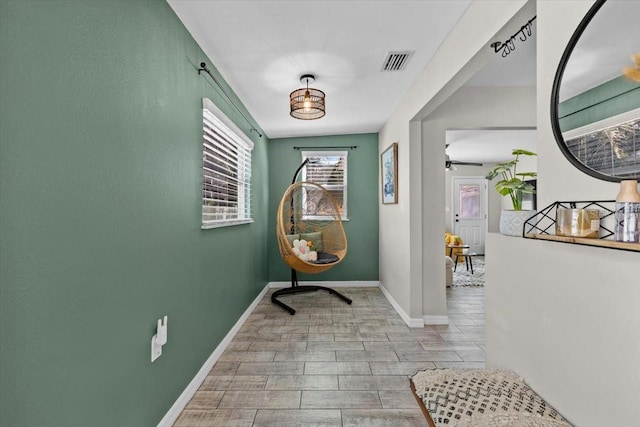 hallway with visible vents, baseboards, and wood tiled floor