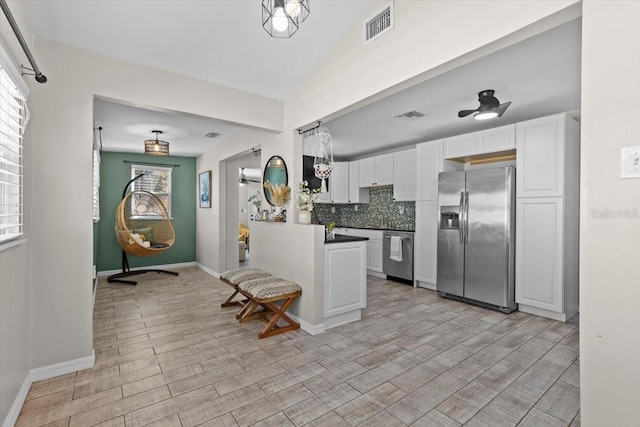 kitchen with dark countertops, visible vents, decorative backsplash, appliances with stainless steel finishes, and white cabinets