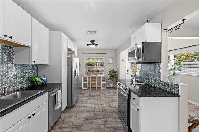 kitchen with visible vents, plenty of natural light, dark countertops, appliances with stainless steel finishes, and white cabinets