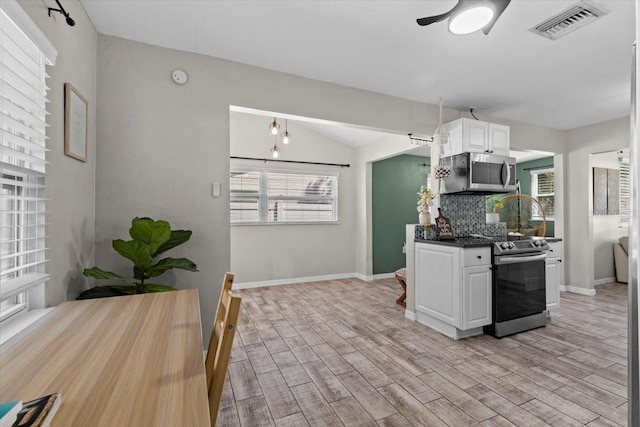 kitchen featuring visible vents, stainless steel appliances, light wood-style floors, and decorative backsplash