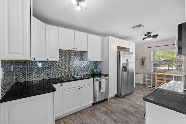 kitchen featuring dark countertops, white cabinets, appliances with stainless steel finishes, and a sink