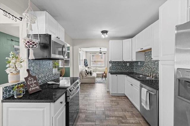 kitchen with a sink, dark countertops, ceiling fan, and stainless steel appliances