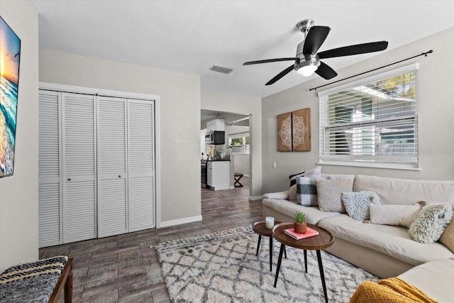 living room featuring visible vents, wood finished floors, baseboards, and ceiling fan