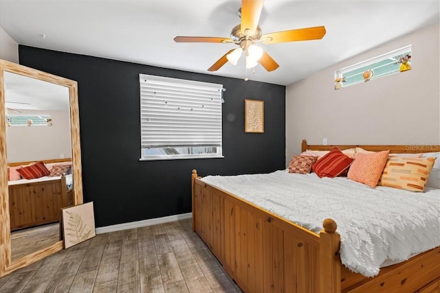 bedroom with baseboards, light wood-style floors, and a ceiling fan