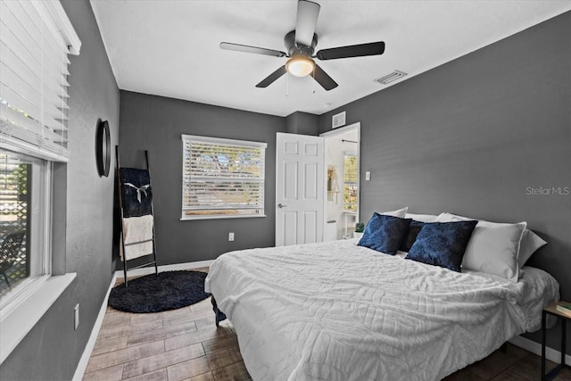 bedroom with a ceiling fan, visible vents, wood finished floors, and baseboards