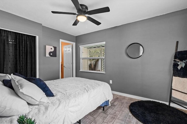 bedroom with ceiling fan, baseboards, and wood finished floors