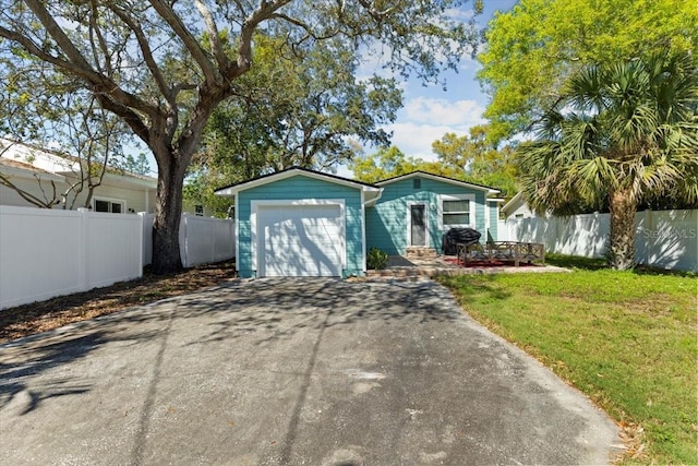 view of front of property featuring a garage, a front yard, driveway, and fence