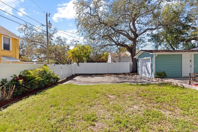 view of yard featuring an outbuilding, a fenced backyard, and a garage