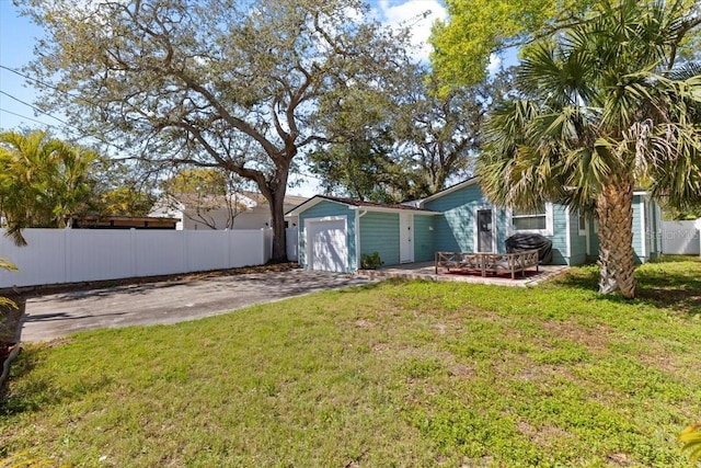 view of yard with fence, a garage, and driveway