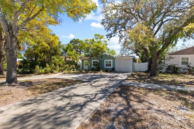 ranch-style home featuring concrete driveway and fence