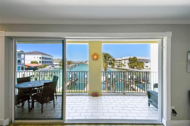 doorway to outside featuring crown molding, baseboards, and a water view