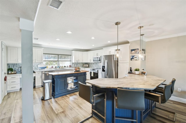 kitchen featuring visible vents, light wood finished floors, white cabinets, appliances with stainless steel finishes, and a center island