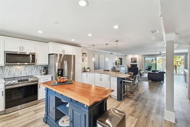 kitchen featuring appliances with stainless steel finishes, white cabinetry, wood counters, and blue cabinets