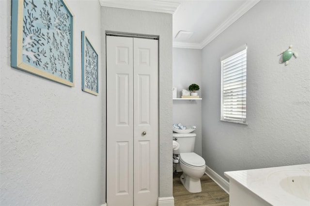 bathroom featuring toilet, wood finished floors, a closet, crown molding, and vanity