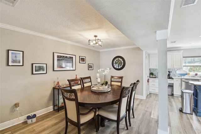 dining room featuring visible vents, baseboards, light wood-style flooring, and crown molding