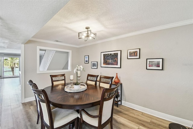 dining space featuring a textured ceiling, crown molding, and light wood finished floors