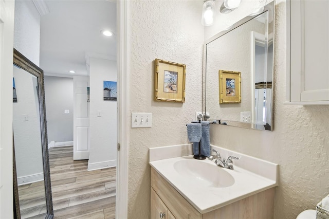 bathroom with recessed lighting, wood finished floors, vanity, and a textured wall