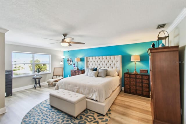 bedroom featuring wood finished floors, visible vents, baseboards, ceiling fan, and ornamental molding