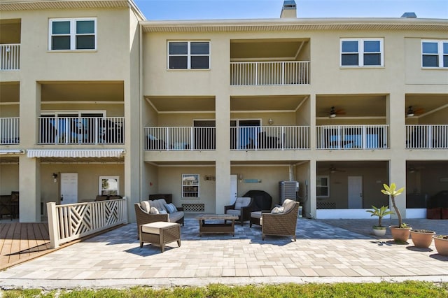 rear view of house with outdoor lounge area, a patio area, a chimney, and stucco siding