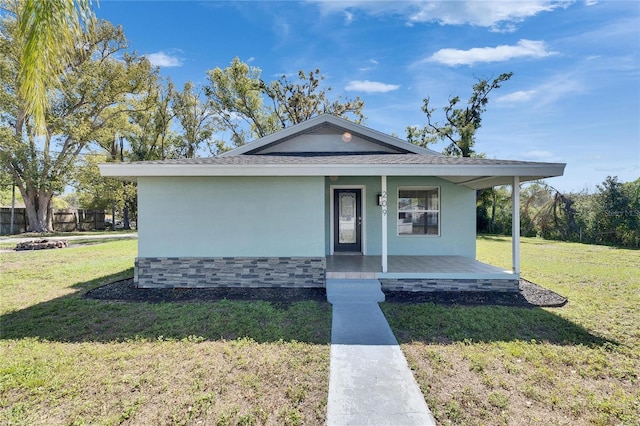 view of front of property with a front lawn, covered porch, and stucco siding