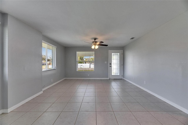 empty room featuring light tile patterned flooring, baseboards, visible vents, and ceiling fan