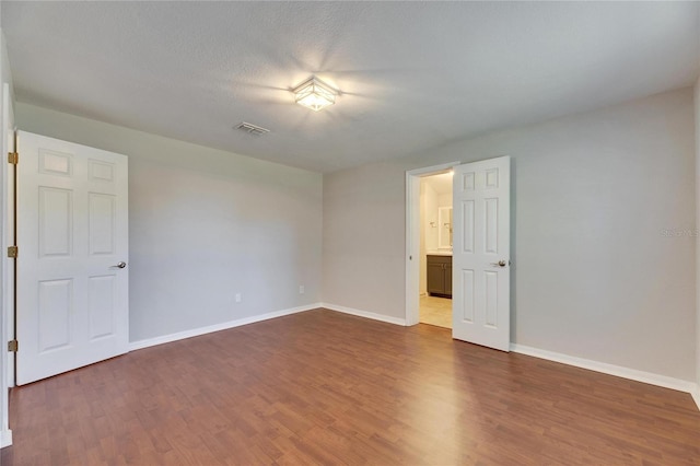 unfurnished room featuring dark wood finished floors, visible vents, a textured ceiling, and baseboards