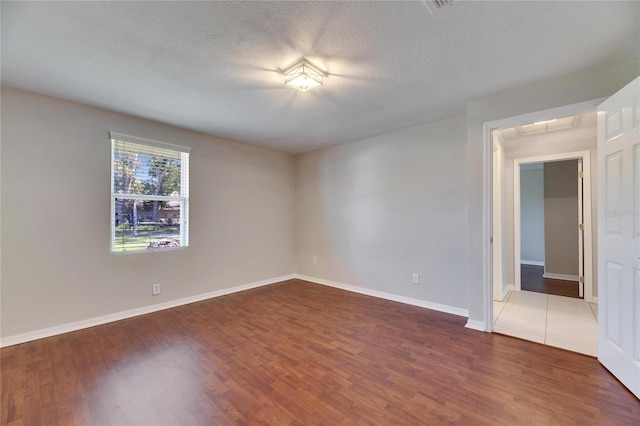 unfurnished room featuring baseboards, a textured ceiling, and wood finished floors