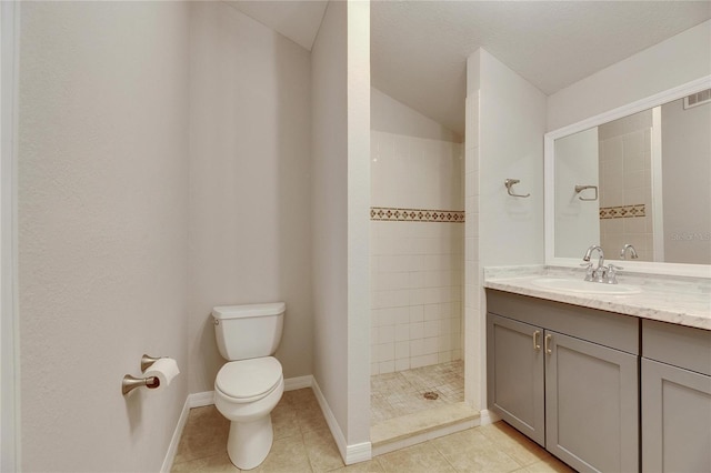 full bathroom with tile patterned floors, toilet, a tile shower, baseboards, and vanity