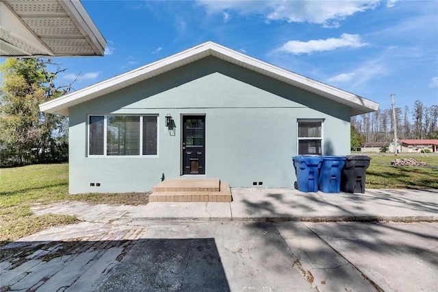 back of property with crawl space, a yard, and stucco siding