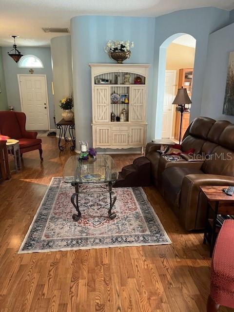 living room featuring visible vents, wood finished floors, and arched walkways