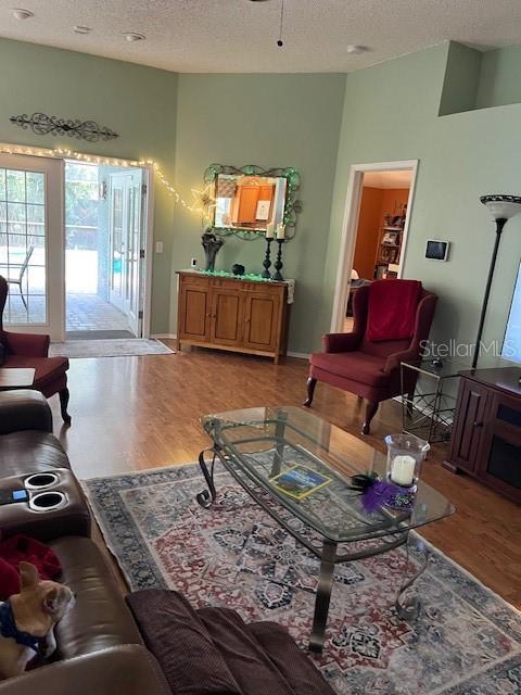 living room with a textured ceiling, baseboards, and wood finished floors