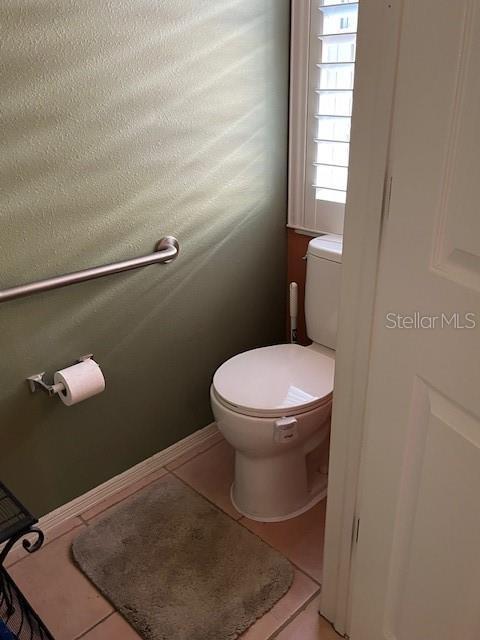 bathroom with tile patterned floors, toilet, and baseboards