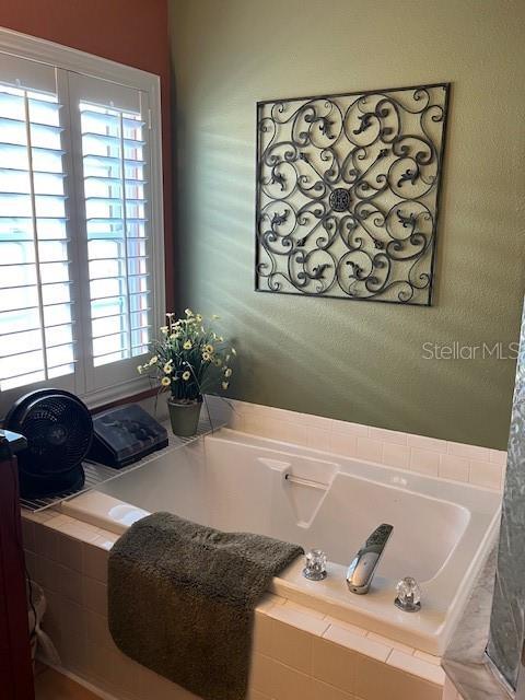 full bathroom featuring a bath and a textured wall