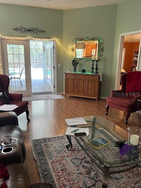 living room with light wood finished floors, a textured ceiling, and baseboards