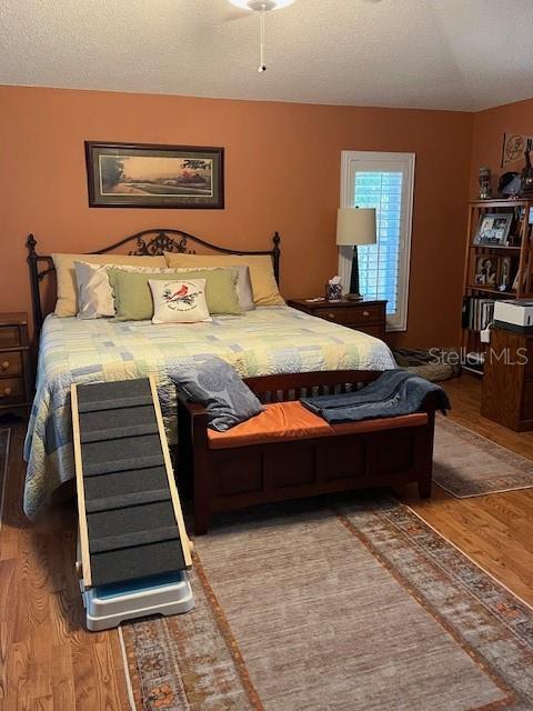 bedroom with a textured ceiling and wood finished floors