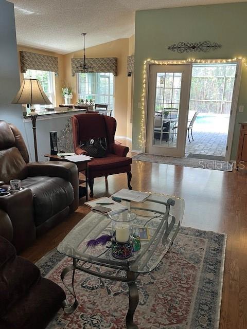 living room with a textured ceiling, lofted ceiling, and wood finished floors