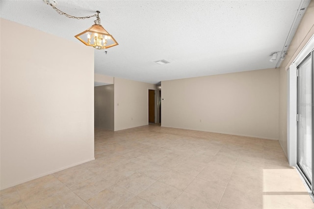 unfurnished room featuring a chandelier, visible vents, a textured ceiling, and baseboards