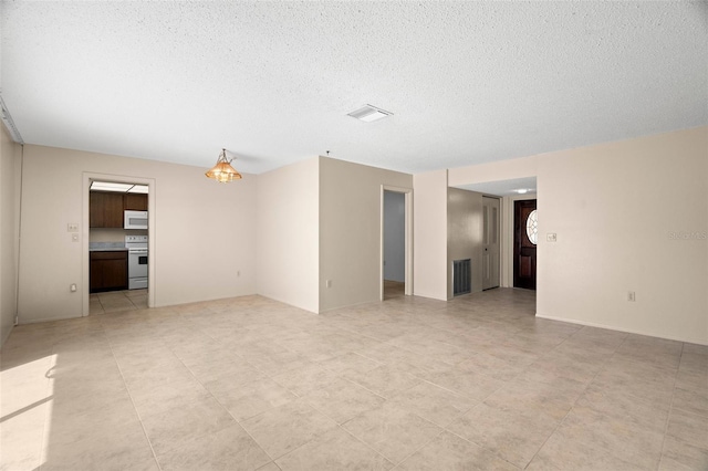 unfurnished living room featuring baseboards, visible vents, and a textured ceiling