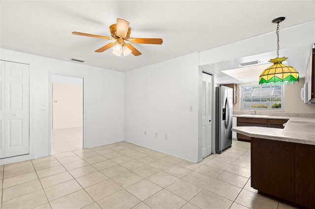 interior space featuring ceiling fan, light tile patterned floors, visible vents, and a sink