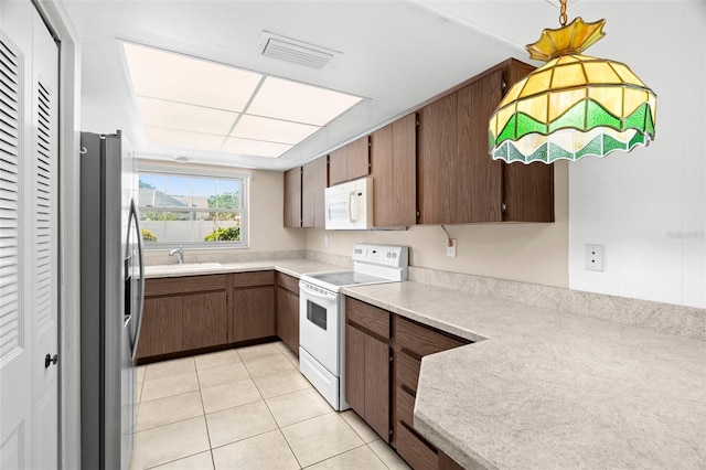 kitchen featuring white appliances, light tile patterned floors, visible vents, a sink, and light countertops