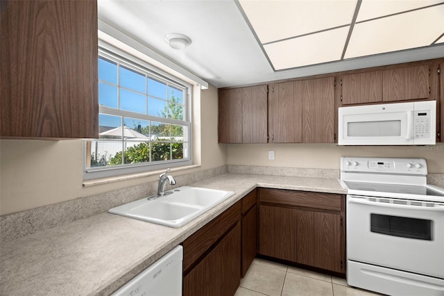 kitchen featuring white appliances, light tile patterned flooring, light countertops, and a sink