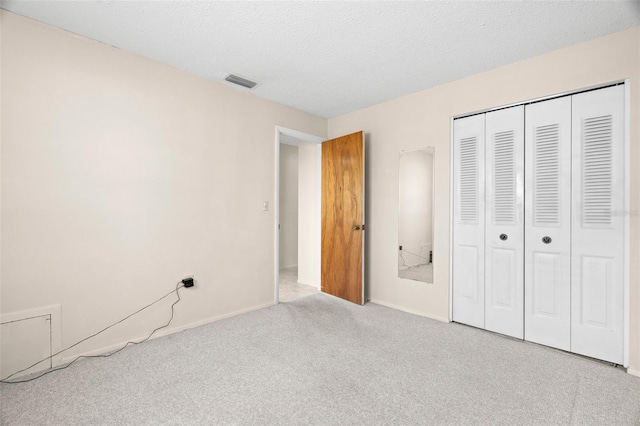 unfurnished bedroom featuring a closet, visible vents, carpet floors, and a textured ceiling