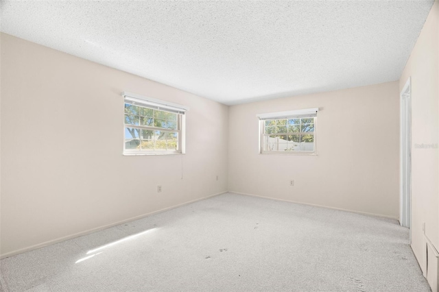 spare room featuring a textured ceiling, a healthy amount of sunlight, and carpet flooring