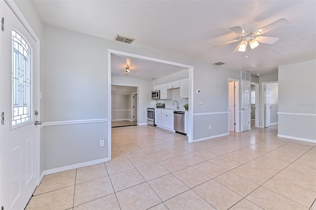 interior space with light tile patterned floors, visible vents, baseboards, and ceiling fan