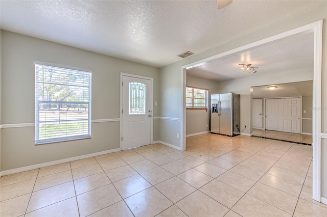 entrance foyer featuring light tile patterned floors, visible vents, baseboards, and a textured ceiling