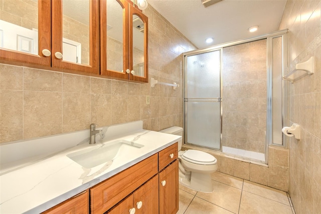 bathroom with tile patterned floors, tiled shower / bath, toilet, tile walls, and vanity