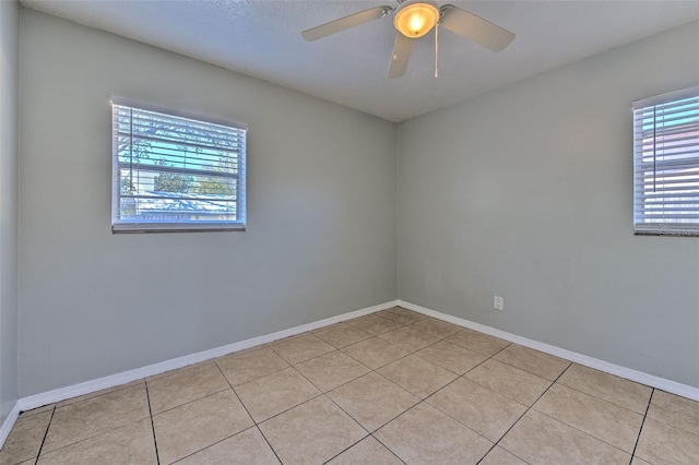 spare room with ceiling fan, baseboards, and light tile patterned flooring