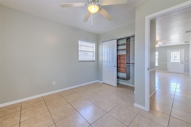 unfurnished bedroom featuring light tile patterned floors, baseboards, a closet, and a ceiling fan