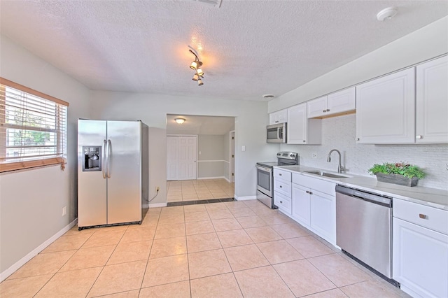 kitchen with a sink, white cabinetry, stainless steel appliances, light countertops, and light tile patterned floors